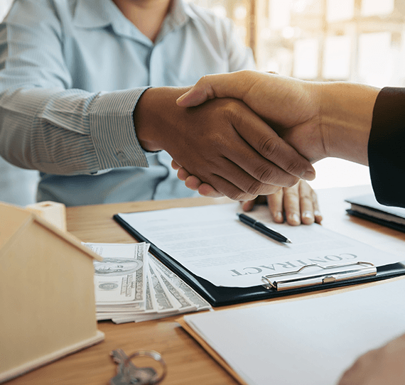 Two people shaking hands after signing a contract signed